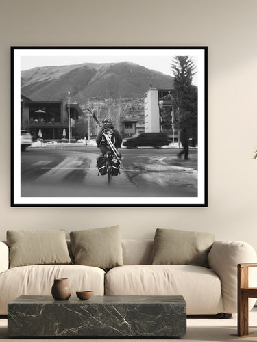 Black wood frame fine art print of Morning Commute by Devon Cardamone, Aspen, CO, displayed on a modern living room wall — downtown Aspen — where the mountain is close enough to bike to with your skis on your back.