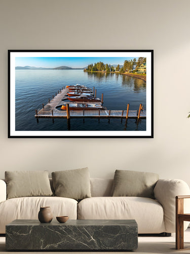 Black wood frame fine art print of Tied Up by Stancraft, Lake Coeur d'Alene, Idaho, displayed on a modern living room wall — stancraft builds fewer than ten wooden boats a year, each one shaped from African mahogany and finished with sixteen coats of hand-buffed varnish.