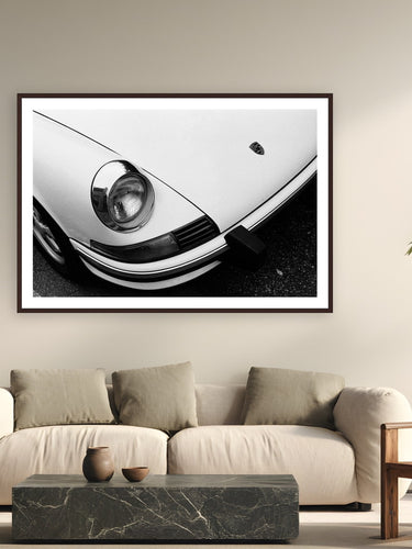 Black wood frame fine art print of Porsche Curves by Adam Sherrett, Venice Beach, California, displayed on a modern living room wall — a classic air-cooled 911 on a Venice Beach street — even parked, it looks fast.