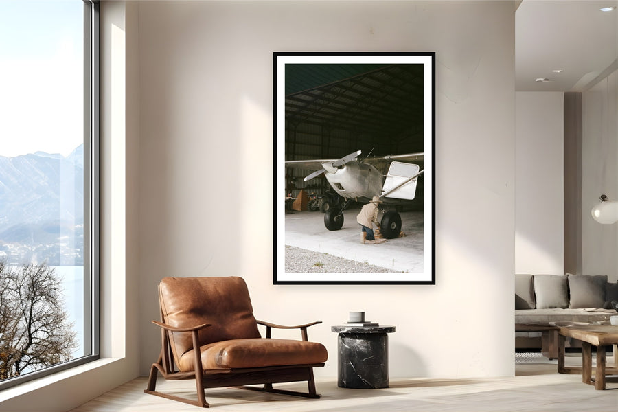 Black wood frame fine art print of Alaskan Transpo by Brooklyn Phillips, McCarthy, Alaska, displayed on a reading nook wall — mcCarthy, Alaska — a town of about two dozen winter residents, where bush planes replace cars and a hand-drawn map counts as GPS.