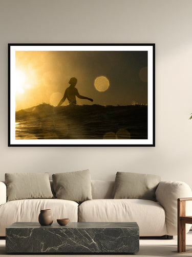 Black wood frame fine art print of Sunscaped by Jeremy Bishop, Malibu, CA, displayed on a modern living room wall — shot from the water at Malibu — the rings of light are saltwater on the housing, backlit by a sun about to drop into the Pacific.