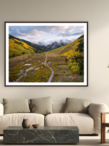 When Mountains Dream in Gold by Sam Ferguson from Ashcroft, Colorado - framed black frame fine art photography displayed in a modern living room setting