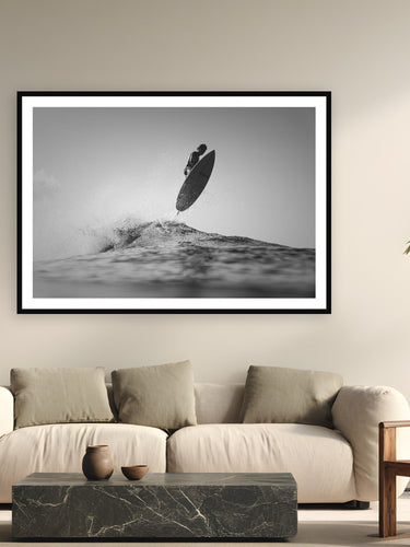 Black wood frame fine art print of Sky High by Sarah Swan, St. John, USVI, displayed on a modern living room wall — a hurricane swell on St. John's north shore — glassy, overhead, and shot from the water.